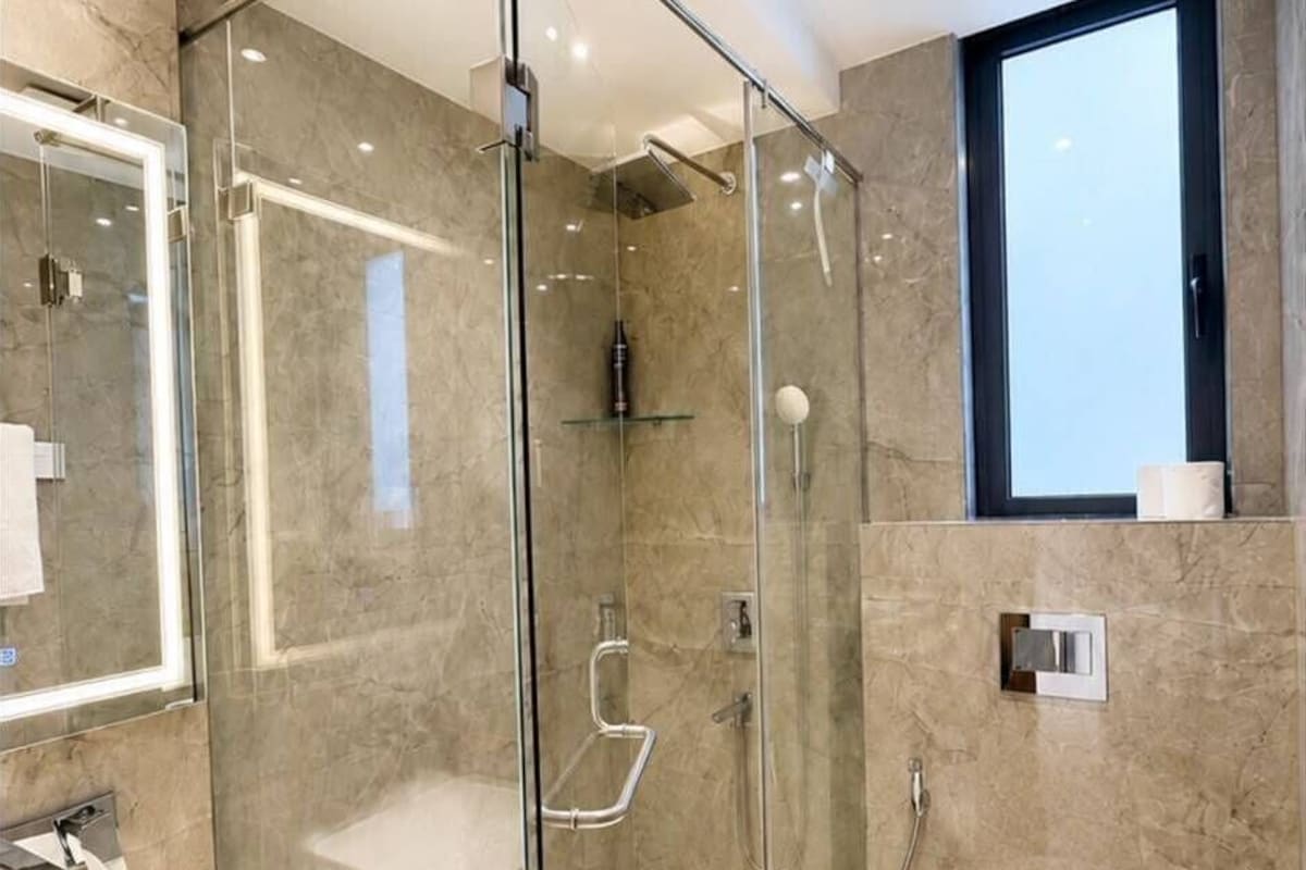 Ein modernes Badezimmer mit einer Duschkabine, einem weißen Waschbecken und einer Toilette.