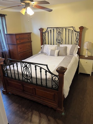 A bedroom with a wooden bed, a nightstand, a dresser, and a ceiling fan. - A wonderful modern home… (New Orleans)