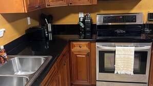 A kitchen with wooden cabinets, a stainless steel sink, a microwave, a stove, and a toaster. - A wonderful modern home… (New Orleans)