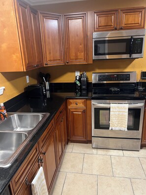A kitchen with wooden cabinets, a stainless steel sink, a microwave, a stove, and a toaster. - A wonderful modern home… (New Orleans)