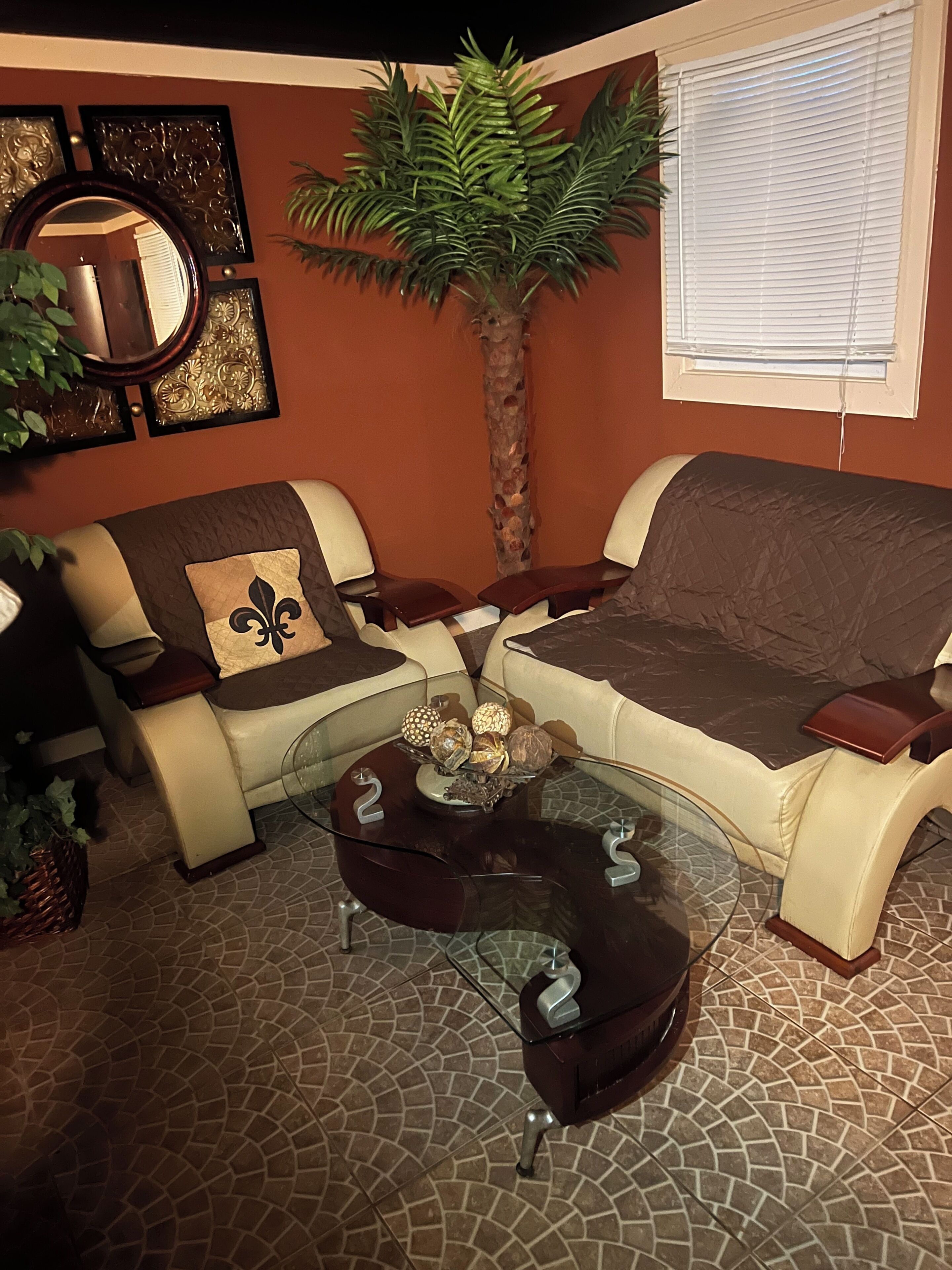 Un salon comprenant un canapé, des fauteuils, une table basse, une plante décorative et un miroir fixé au mur.