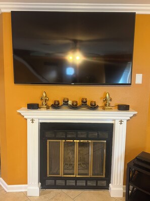 A fireplace with a flat-screen TV mounted above it. - A wonderful modern home… (New Orleans)