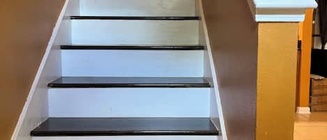 A staircase with white steps and black edges, leading to a landing with a white balustrade.