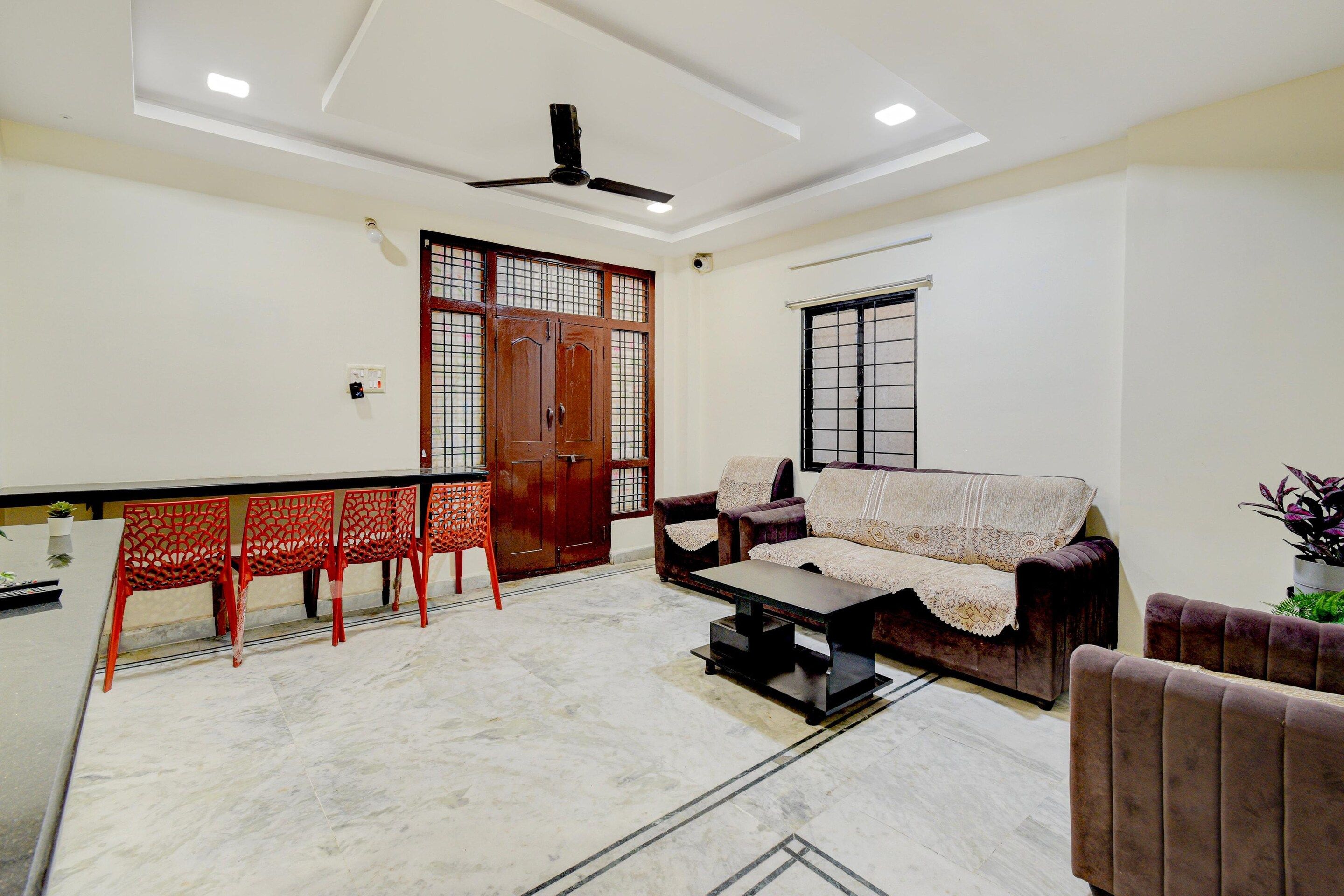 A living room with a sofa, chairs, a coffee table, a ceiling fan, and a window with a metal grill.