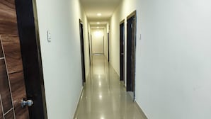 Un couloir bordé de portes des deux côtés, qui mène à une pièce au bout.