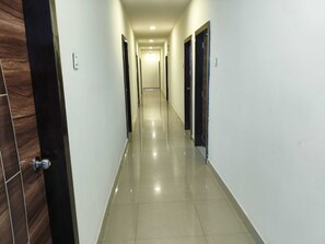 A corridor with doors on both sides, leading to a room at the end. - Classic SLN Terminus Gachibowli (Hyderabad)