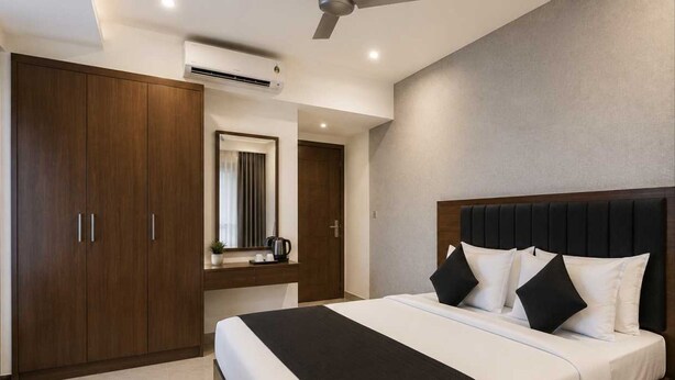 Une chambre d’hôtel moderne équipée d’un grand lit, d’une armoire, d’une coiffeuse avec miroir et d’un appareil de climatisation.
