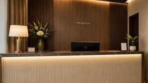 Un comptoir d’accueil avec une lampe, un vase de fleurs et une pancarte indiquant « réception ».