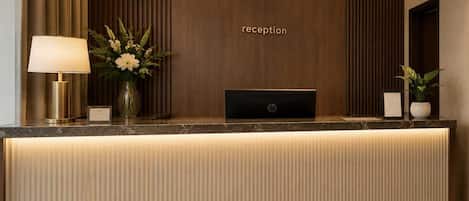 Un mostrador de recepción con una lámpara, un florero y un cartel que dice 'reception'.