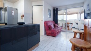 Una cucina moderna con un piano di lavoro nero, un divano rosso e un'area pranzo con mobili in legno.