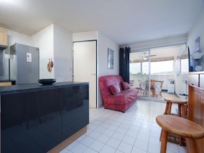 Eine moderne Küche mit schwarzer Arbeitsplatte, einem roten Sofa und einem Essbereich mit Holzmöbeln.