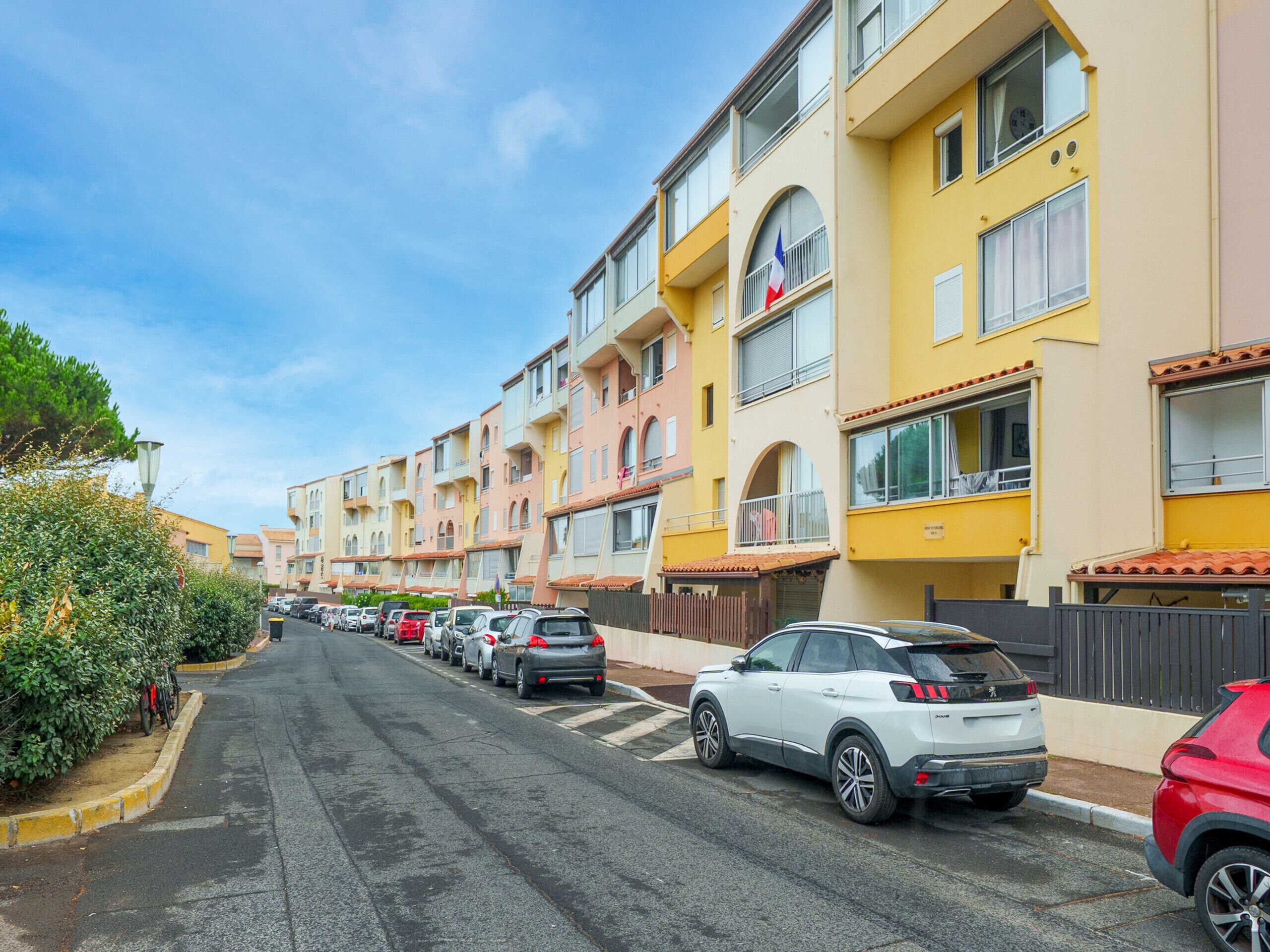 Uma fileira de edifícios residenciais de vários andares, com varandas, e uma rua no meio.
