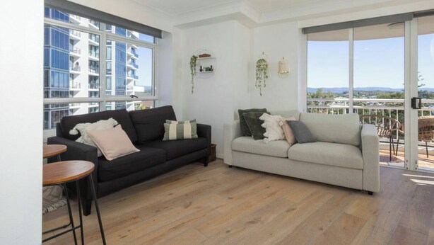 A spacious living area with two sofas, a small table, and a balcony with a view. - Breezy 2BDR Beachfront Apt in Burleigh Heads (Burleigh Heads)