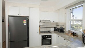 A modern kitchen with a built-in oven, a stovetop, and a refrigerator. - Breezy 2BDR Beachfront Apt in Burleigh Heads (Burleigh Heads)