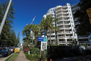 Un hôtel à plusieurs étages doté de balcons, une promenade piétonne et une grue de construction en arrière-plan.