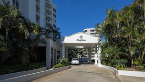 A hotel entrance with a canopy and palm trees. - Breezy 2BDR Beachfront Apt in Burleigh Heads (Burleigh Heads)