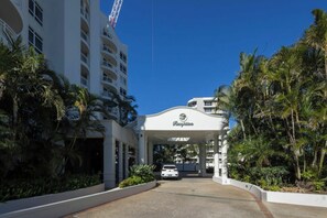 A hotel entrance with a canopy and palm trees. - Breezy 2BDR Beachfront Apt in Burleigh Heads (Burleigh Heads)