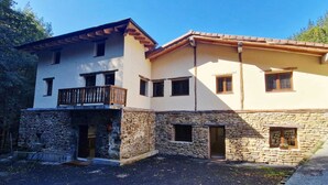 A two-story building with a stone facade, a balcony, and multiple windows. - Jentilbaratze: More Than Just a Country House. Multifunctional space surrounded by nature (Orozko)