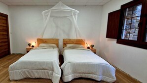 A bedroom with two beds, a wooden floor, a wooden door, a window with a stone frame, and a canopy bed. - Jentilbaratze: More Than Just a Country House. Multifunctional space surrounded by nature (Orozko)