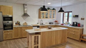 A modern kitchen with wooden cabinets, stainless steel appliances, and pendant lighting. - Jentilbaratze: More Than Just a Country House. Multifunctional space surrounded by nature (Orozko)