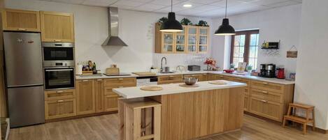 A modern kitchen with wooden cabinets, stainless steel appliances, and pendant lighting.