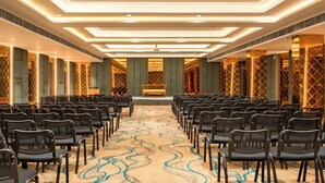 A conference room with rows of chairs, a patterned carpet, and a modern ceiling design. - Midland Residency (Coimbatore)
