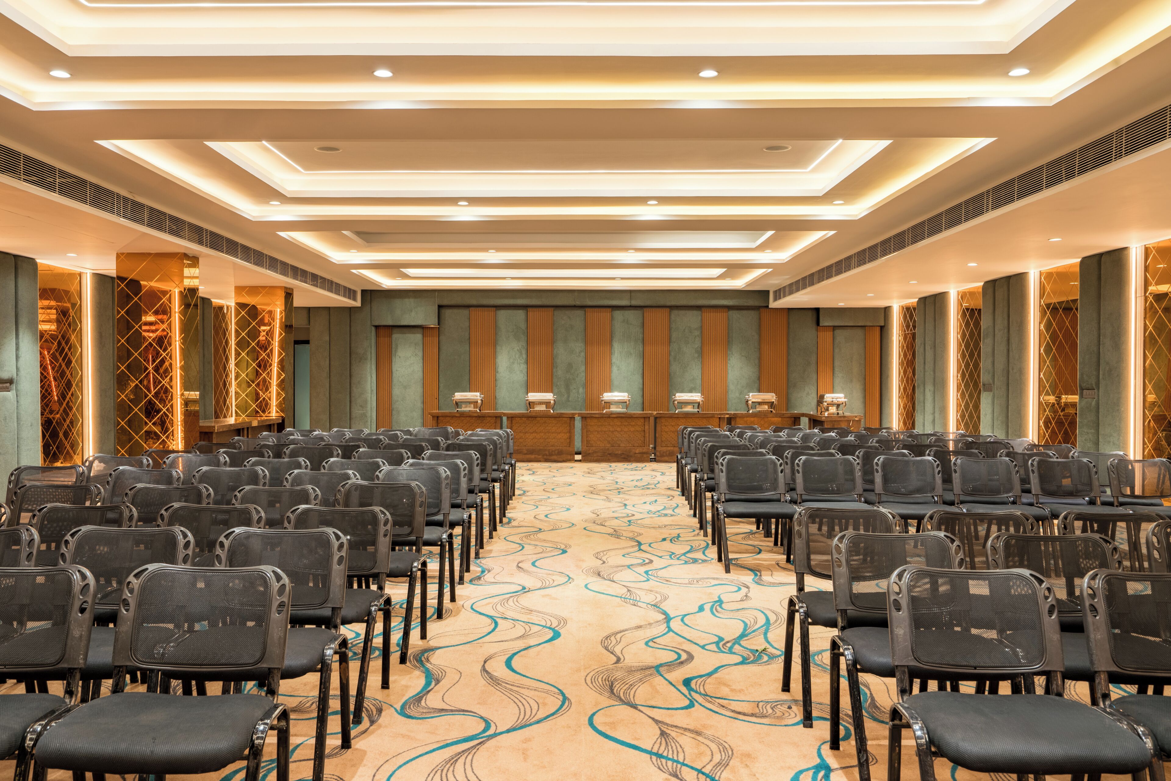 A conference room with rows of chairs, a podium, and a patterned carpet.