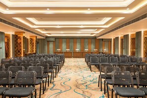 Un salón de conferencias con filas de sillas, un atril y una alfombra estampada.