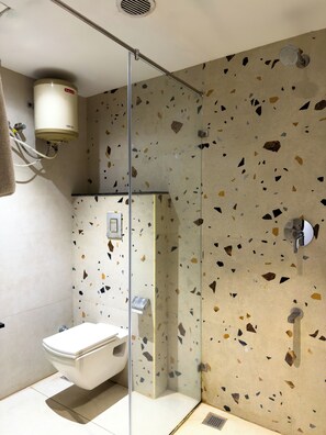 Un baño moderno con ducha separada por vidrio, un inodoro y un calentador de agua instalado en la pared.