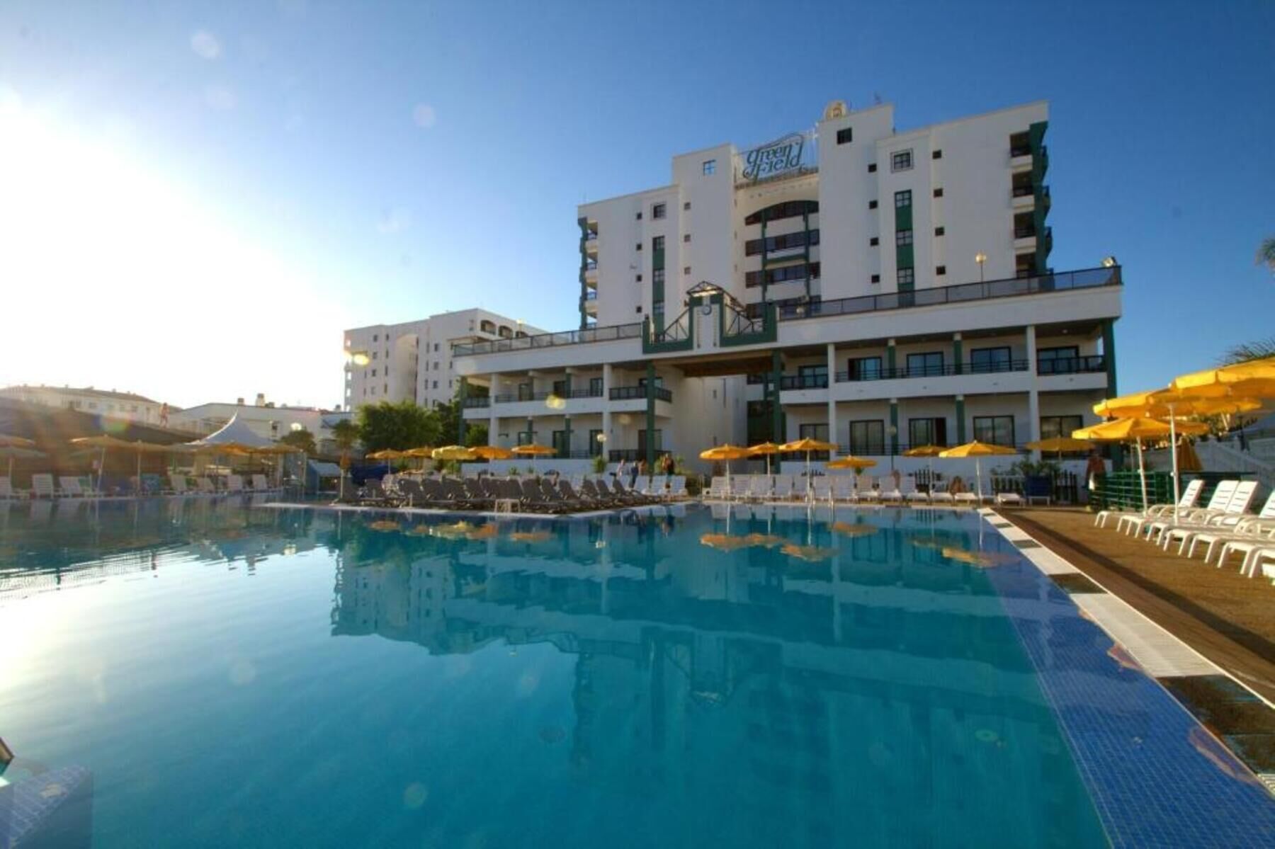 Un hotel con piscina, varios balcones y sombrillas.