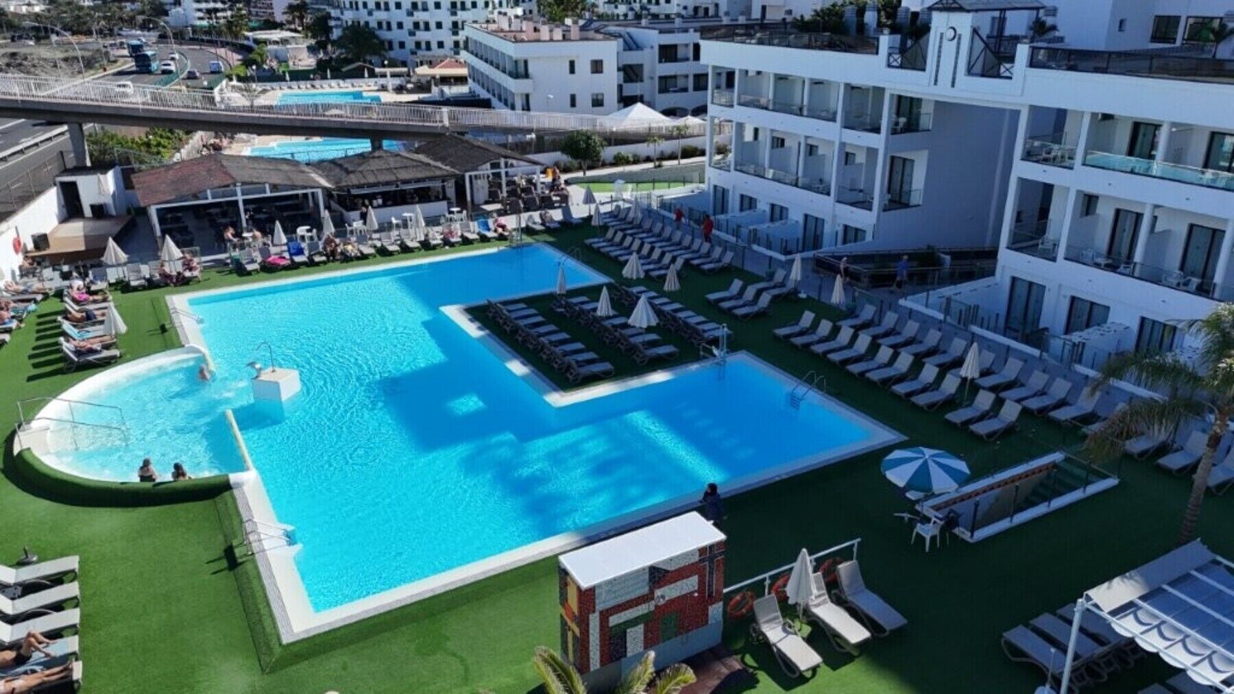 A large swimming pool with multiple sun loungers and a separate smaller pool area.