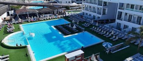 Ein großer Pool mit mehreren Liegestühlen und ein separater, kleinerer Poolbereich.