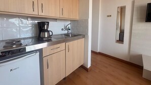 Een moderne keuken met houten kastjes, een koffiezetapparaat, een spoelbak en een compacte vaatwasser.