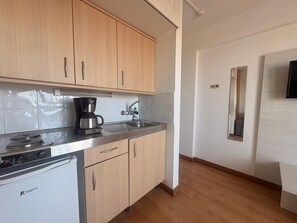 Eine moderne Küche mit Holzausstattung, einer Kaffeemaschine, einem Spülbecken und einem kompakten Geschirrspüler.