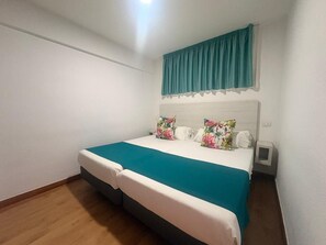 Un dormitorio con una cama individual, una mesita de noche y una ventana con cortinas.