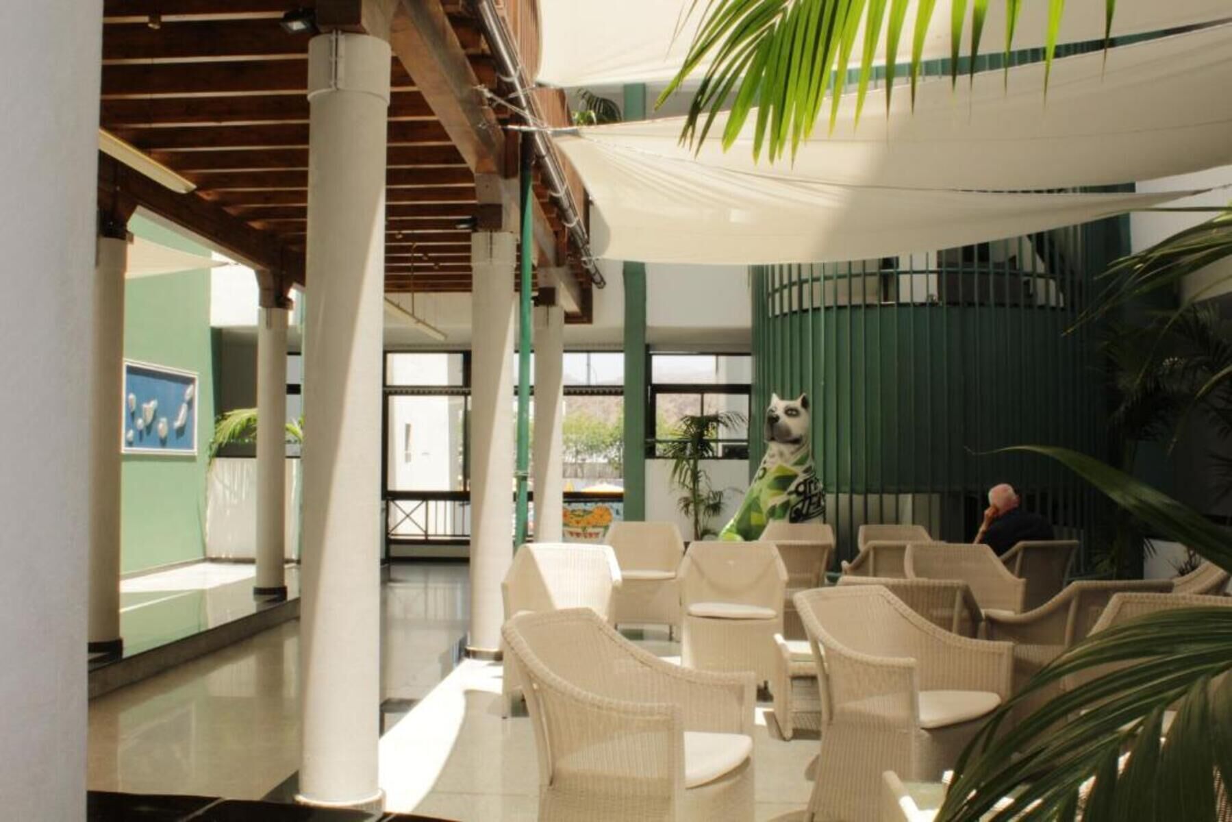 Un espace intérieur spacieux, aménagé avec des meubles en osier, une clôture verte et un auvent blanc.
