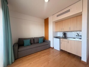 Ein kompakter Wohnraum mit einer Couch, einer Küchenzeile und Holzboden.