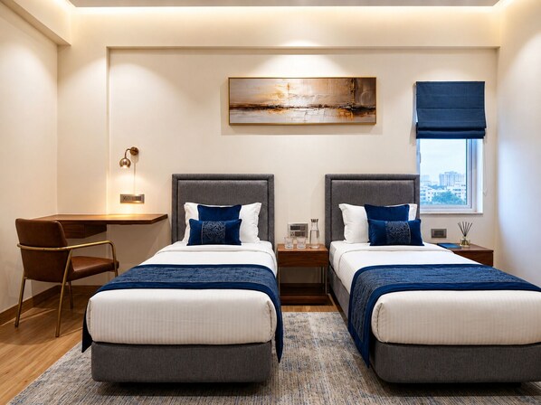Une chambre d’hôtel avec deux lits, un bureau, une chaise, un tableau et une fenêtre donnant sur un beau paysage.
