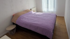 A bedroom with a bed, a small round table, and a window with patterned curtains.