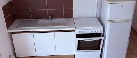 A compact kitchen with white cabinets, a built-in oven, and a refrigerator.