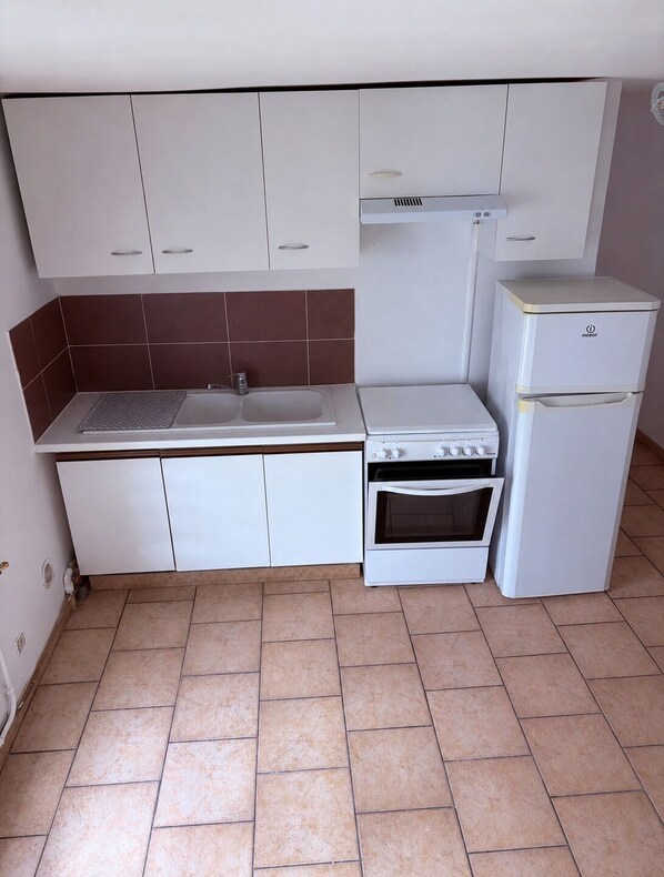 A compact kitchen with white cabinets, a built-in oven, and a refrigerator.