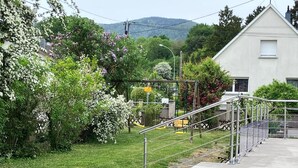 A residential area with a concrete pathway, a metal fence, and a white building.