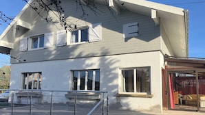 A two-story building with a balcony, large windows, and a visible entrance.