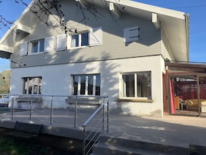 A two-story building with a balcony, large windows, and a visible entrance.
