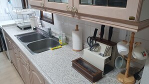 Een keuken met twee spoelingen, een afdruiprek, een keukenrolhouder en een bestekhouder.