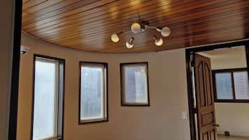 A room with a wooden ceiling, three windows, and a door.