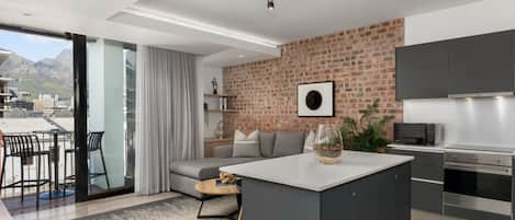 A modern kitchen with a brick wall, a dining area with a sofa, and a view of the city.