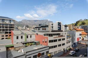 Ein mehrstöckiges Gebäude mit Dachterrasse, einem gut sichtbaren Schild und einem Berg im Hintergrund.