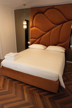 Ein Hotelzimmer mit einem großen Bett, Holzboden und einem modernen Kopfteil.