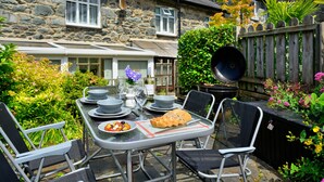 A stone house with a garden patio, outdoor dining set, and a wooden fence. - Artro View (Llanbedr)